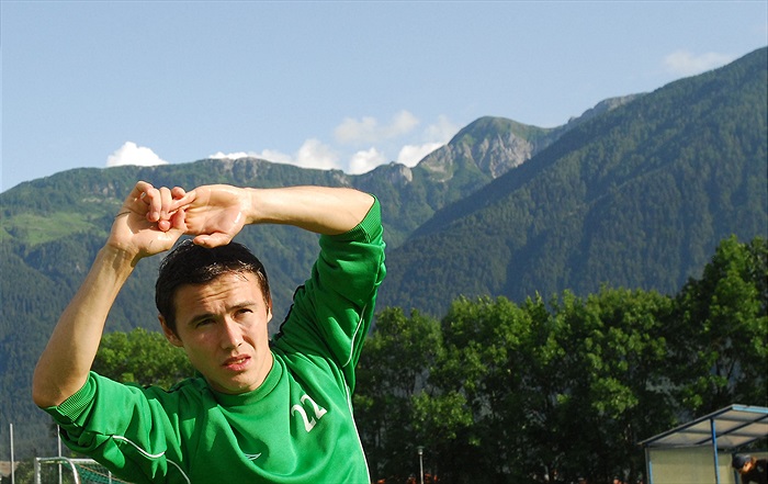 Aziz Ibragimov se rozvičuje pod vrcholky hor.